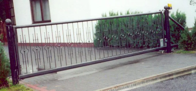 Freitragendes Schiebetor mit Zierstäben und Antriebssäule an einer Grundstückseinfahrt