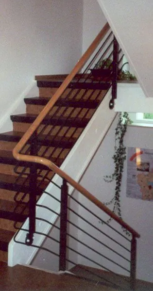 Treppengeländer aus Stahl mit waagerechten Rundstäben und Holzhandlauf in einem Treppenhaus