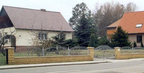Schmiedeeiserne Zaunfelder auf einer Klinkermauer mit Pfeilern und einem Doppeltor