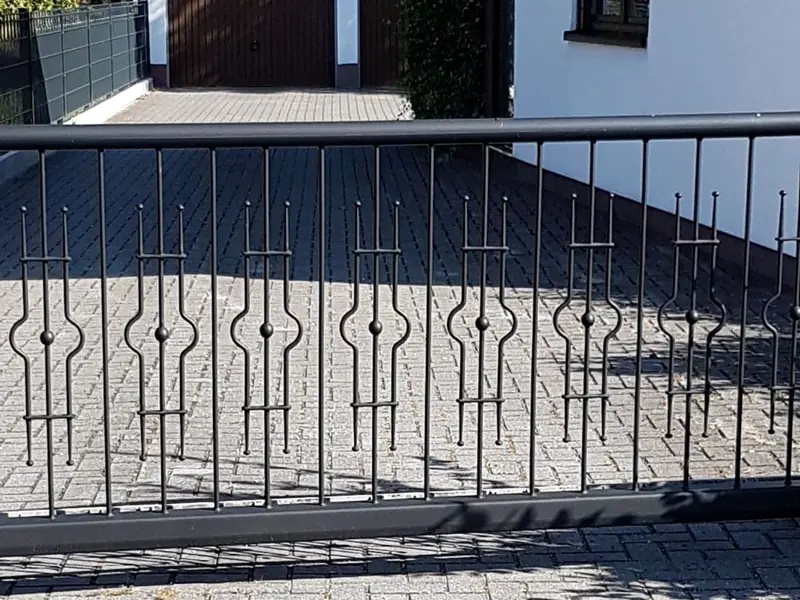 Schiebetor in Anthrazit mit Zierstäben und Kugelornamenten vor einer gepflasterten Einfahrt